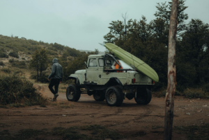 Off-road truck carrying kayak in rain.